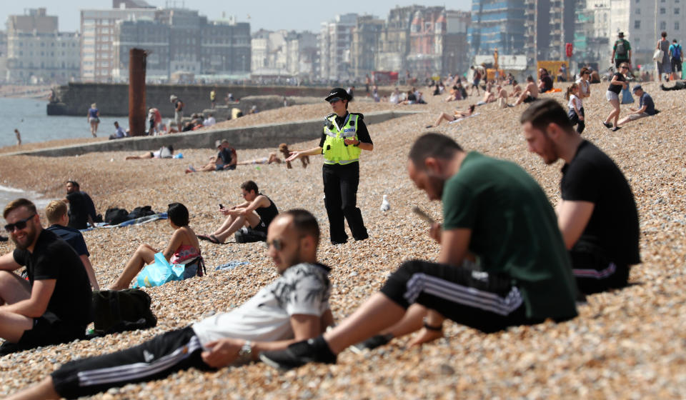 A police officer advises people to leave the beach during the warm weather in Brighton as the UK continues in lockdown to help curb the spread of the coronavirus.