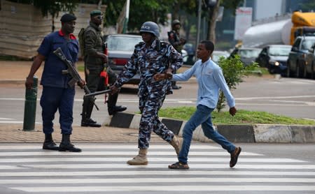 A police officer detains a young man after police dispersed members of the IMN from a street in Abuja