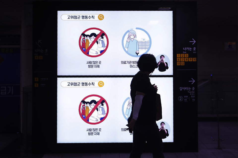 A woman wearing a mask passes screens showing social behavior rules to help curb the spread of the coronavirus at a subway station in Seoul, South Korea, Thursday, Aug. 27, 2020. South Korea has added nearly 4,000 infections to its caseload while reporting triple-digit daily jumps in each of the past 14 days, prompting health experts to warn about hospitals possibly running out of capacity. The sign reads: "Do not visit crowded places." (AP Photo/Ahn Young-joon)