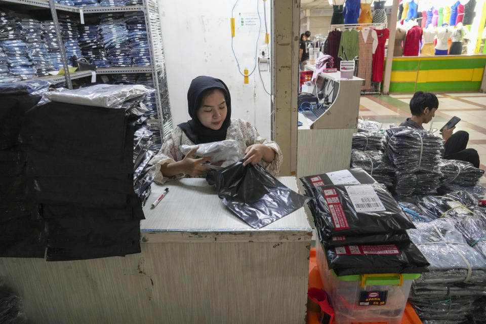 A trader wraps merchandise to send her customer she's dealing with by live sale via streaming at a store in the Tanah Abang textile market in Indonesia Thursday, Sept. 28, 2023. Chinese-owned app TikTok on Thursday said it regretted the Indonesian government's decision to ban e-commerce transactions on social media platforms, particularly the impact it would have on the millions of sellers who use TikTok Shop. (AP Photo/Tatan Syuflana)