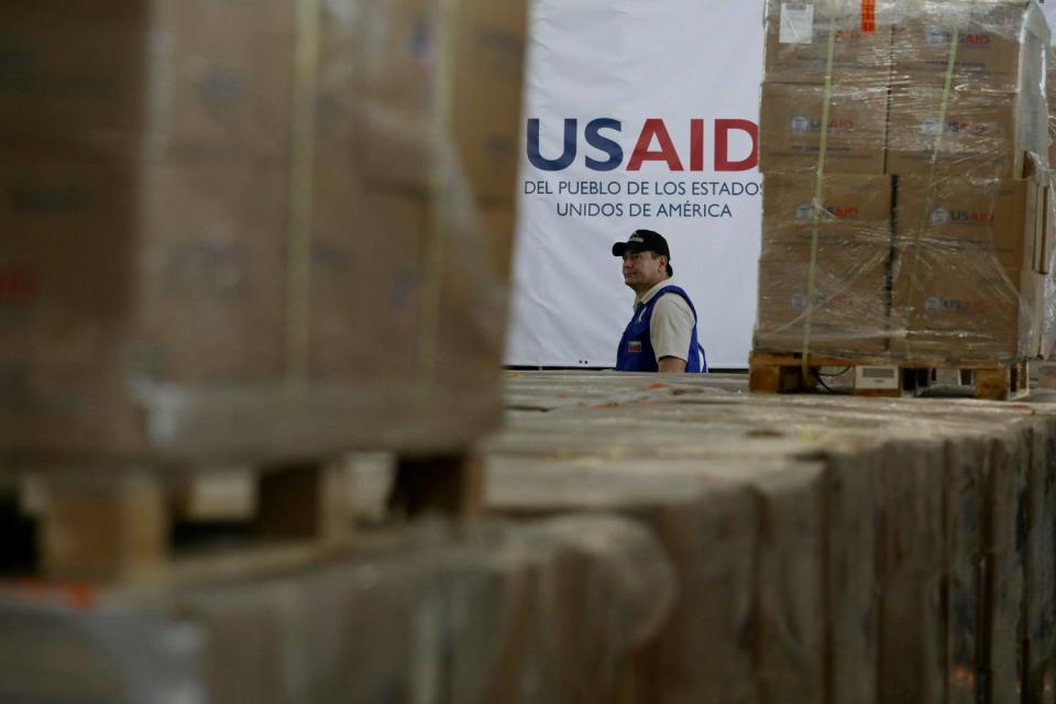 A man walks past boxes of stockpiled USAID humanitarian aid meant for Venezuela at a warehouse in Colombia. 