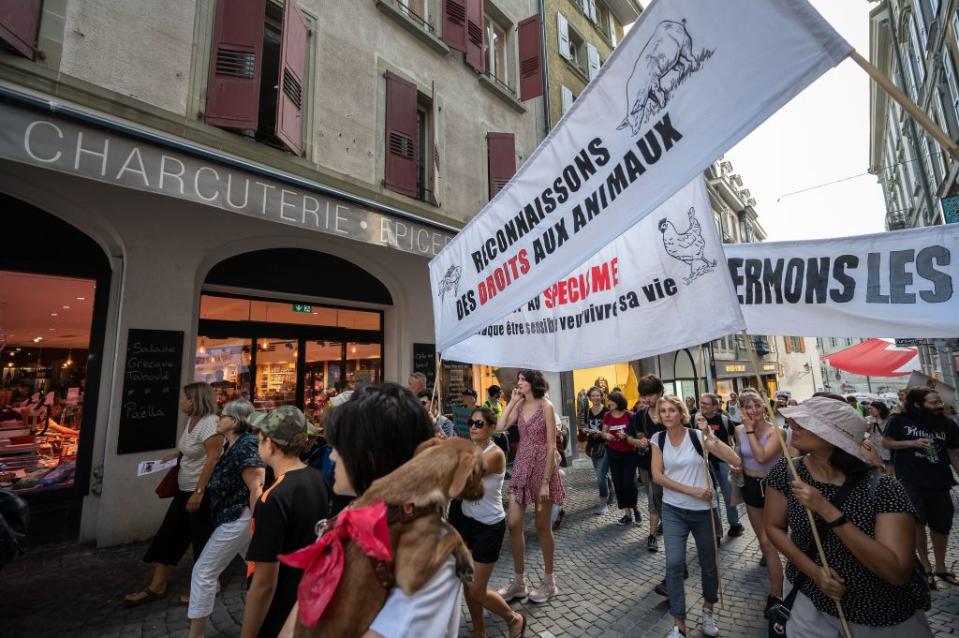 Activists hold a banner reading in French "let's recognize some rights for animals" as they walk past a delicatessen during a protest in Lausanne, western Switzerland on Aug. 27, 2022.<span class="copyright">Fabrice Coffrini—AFP/Getty Images</span>