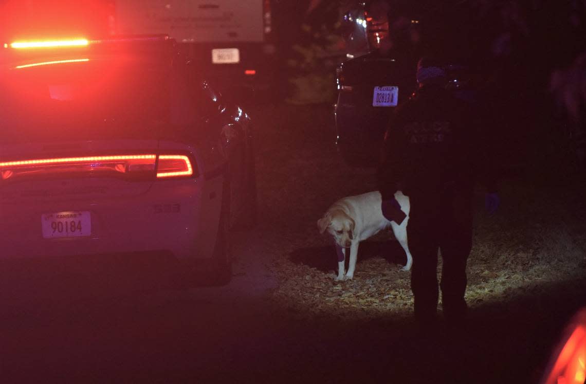 An investigator with the Bureau of Alcohol, Tobacco and Firearms leads a police dog through the scene of a shooting in Kansas City, Kansas where seven people were shot, one fatally, during a large gathering at a home in the 1600 block of South 50th Street.