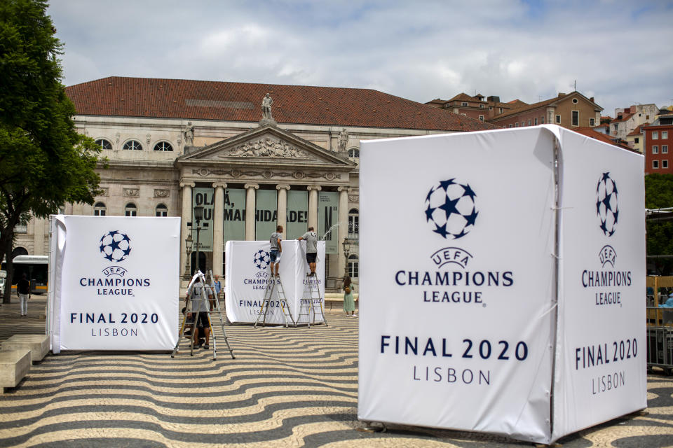 Staff workers set up banners of the UEFA Champions League in downtown Lisbon, Portugal, Wednesday, Aug. 12, 2020. The country has the center stage from Wednesday when eight of Europe's best teams start fighting for the coveted Champions League title amid strict health protocols.(AP Photo/Manu Fernandez)