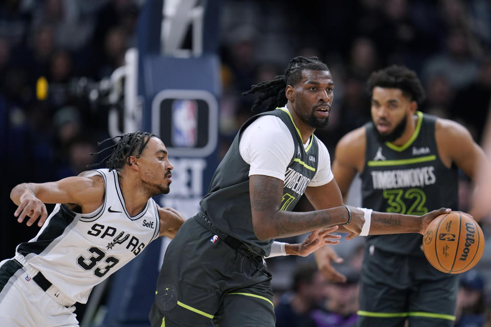 Minnesota Timberwolves center Naz Reid is defended by San Antonio Spurs guard Tre Jones (33) during the first half of an NBA basketball game Wednesday, Dec. 6, 2023, in Minneapolis. (AP Photo/Abbie Parr)