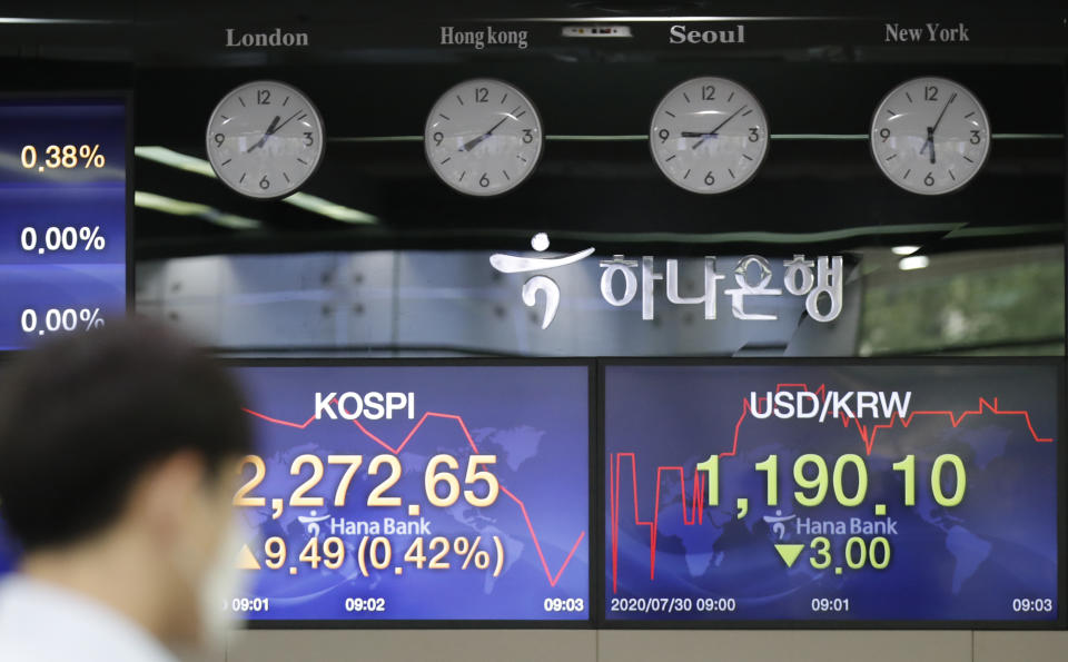 A currency trader walks near the screens showing the Korea Composite Stock Price Index (KOSPI), left, and the foreign exchange rate between U.S. dollar and South Korean won at the foreign exchange dealing room in Seoul, South Korea, Thursday, July 30, 2020. Asian stocks advanced Thursday after the U.S. Federal Reserve left interest rates near zero to support a struggling economy. (AP Photo/Lee Jin-man)