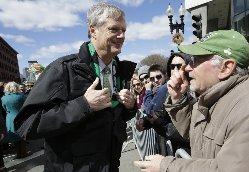 Massachusetts Gov. Charlie Baker, left, displays his green tie to a spectator at the start of the annual St. Patrick's Day parade, Sunday, March 17, 2019, in Boston's South Boston neighborhood. The city celebrated the holiday with crowds lining the route of the 118th edition of the parade. (AP Photo/Steven Senne)