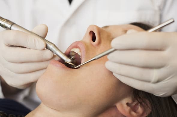 Caucasian dentist examining woman's teeth in office