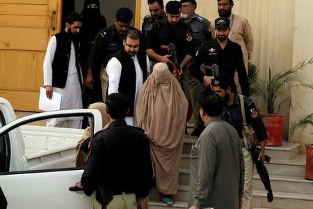 Policemen escort Sharbat Gula (C), the green-eyed Afghan woman who became a symbol of her country's wars 30 years ago when her photo as a girl appeared on the cover of National Geographic magazine, as she leaves after appearing before a court in Peshawar, Pakistan, November 4, 2016. REUTERS/Fayaz Aziz