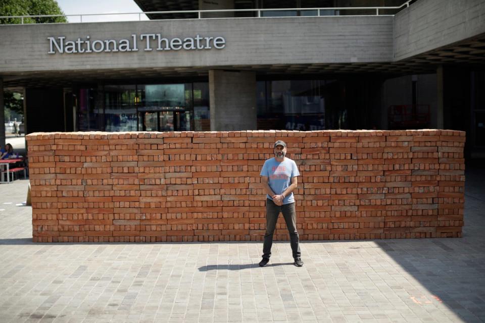 Mexican artist Bosco Sodi poses for photographs in front of his performative installation 'Muro' (wall), an 8 meter long wall in the riverside square of the National Theatre, LOndon (AP)