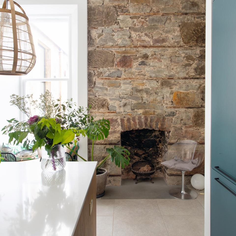 Exposed stone in the kitchen with plants and an island unit