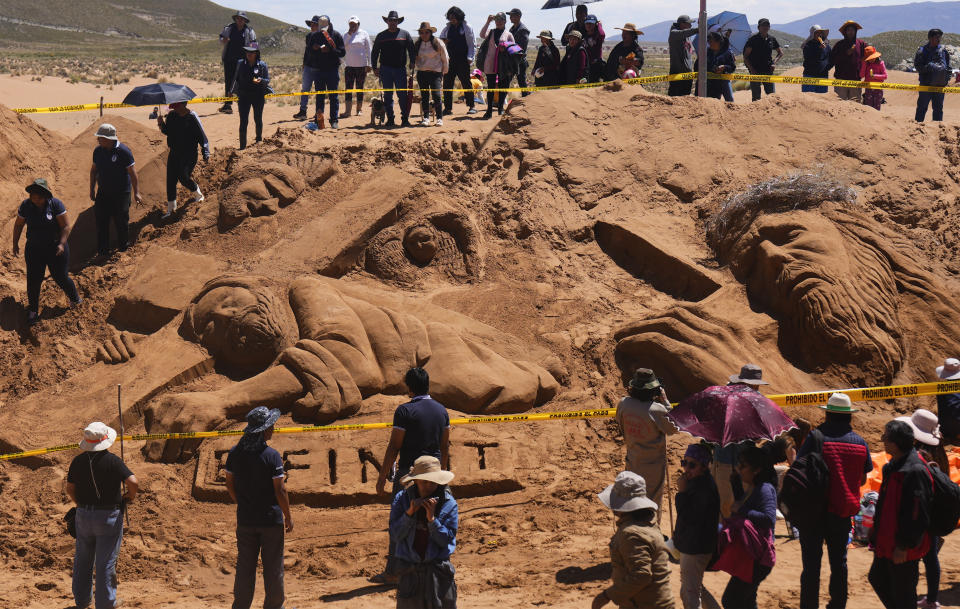 People gather round sand sculptures depicting Jesus Christ on a cross as part of Holy Week celebrations, in Los Arenales de Cochiraya, on the outskirts of Oruro, Bolivia, Good Friday, March 29, 2024. Artists gathered for the annual Holy Week event in the highland region, building sand sculptures based on Bible stories. (AP Photo/Juan Karita)