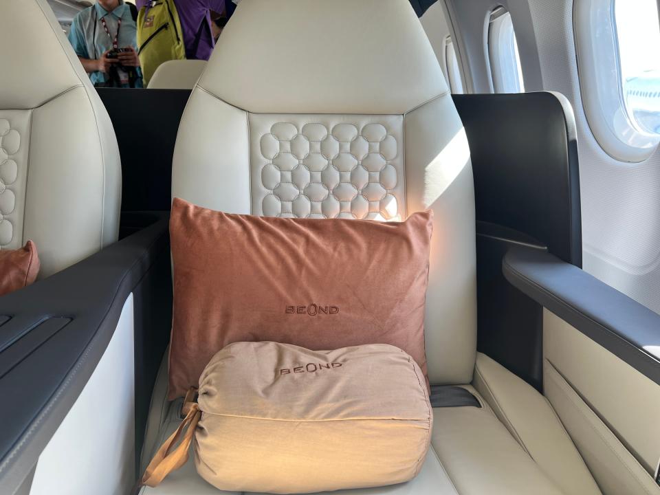 A close-up of the orange cushion and a Beond-branded bag on a cream seat of its A319