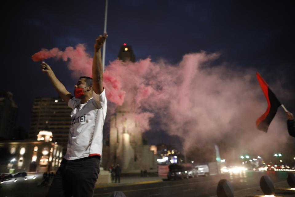 A man wearing a protective face mask holds flares during a caravan organized by the soccer club fans of Newell's Old Boys in the hometown of Leonel Messi, in Rosario, Argentina, Thursday, Aug. 27, 2020. Fans hope to lure him home following his announcement that he wants to leave Barcelona F.C. after nearly two decades with the Spanish club. (AP Photo/Natacha Pisarenko)