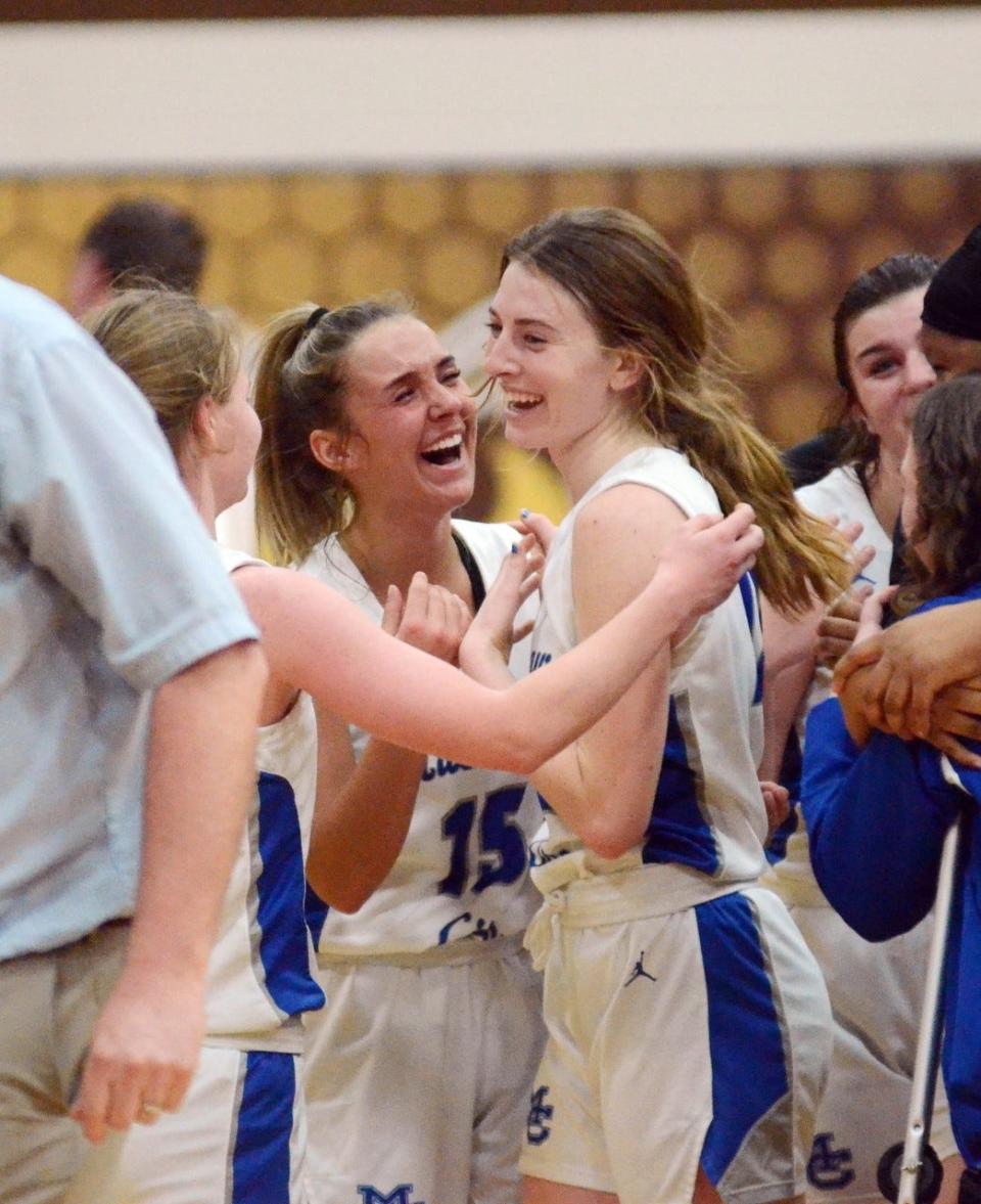 Mackinaw City's Marlie Postula (middle) and Larissa Huffman (right) celebrate, with teammate Gracie Beauchamp (left) coming in for a hug.