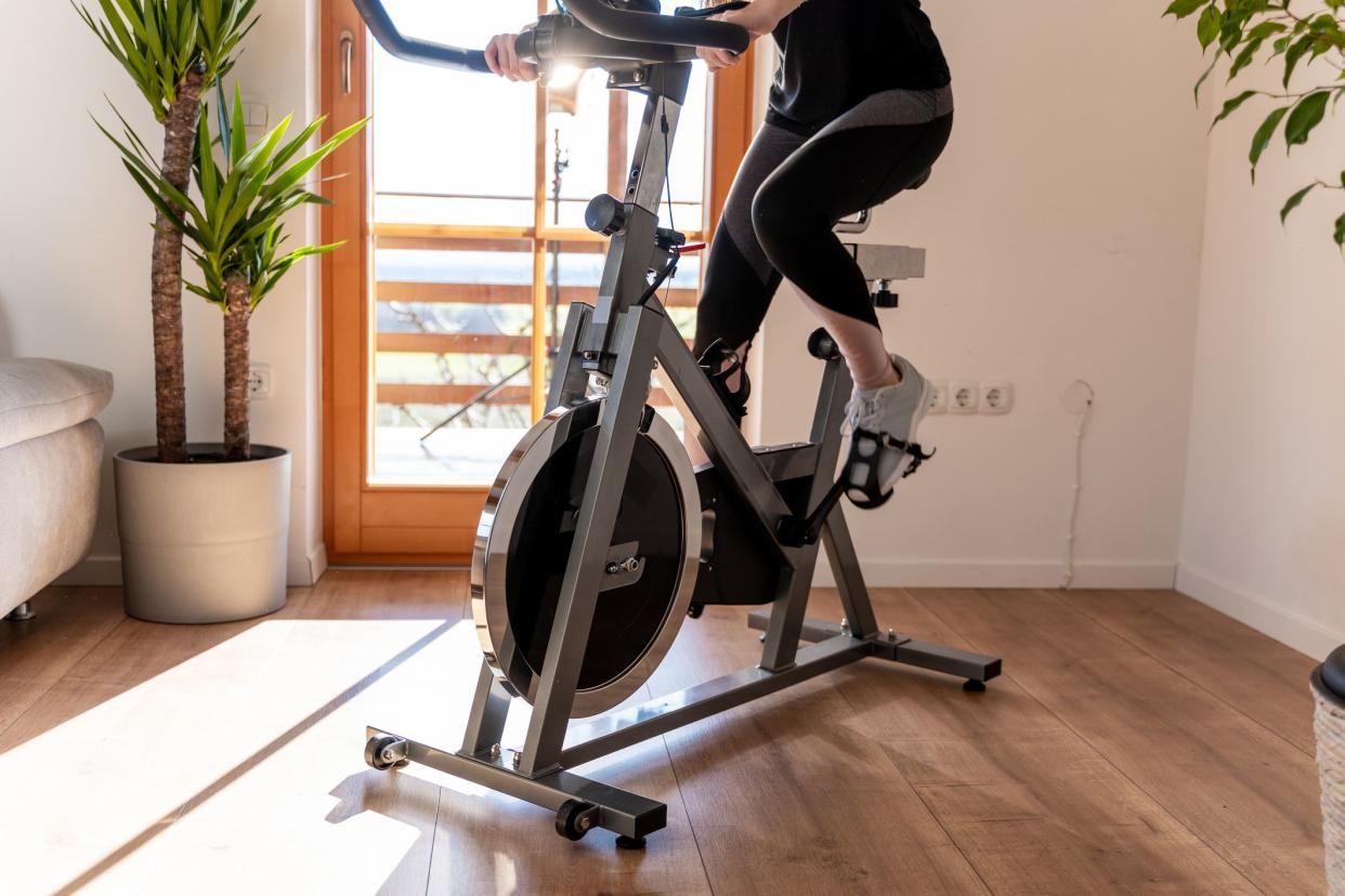 Low section view of a young woman in sportswear exercising on exercise bike at home