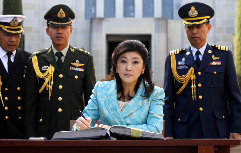 FILE - In this May 28, 2012 file photo, Thai Prime Minister Yingluck Shinawatra, center, signs the visitors book at the Australian War Memorial in Canberra, Australia. As she marks a year in office this weekend as Thailand's first female prime minister, Yingluck's biggest boast could be about what hasn't happened during that time: a return to the chaos that has wracked the country for much of the past six years. (AP Photo/Lukas Coch, File)