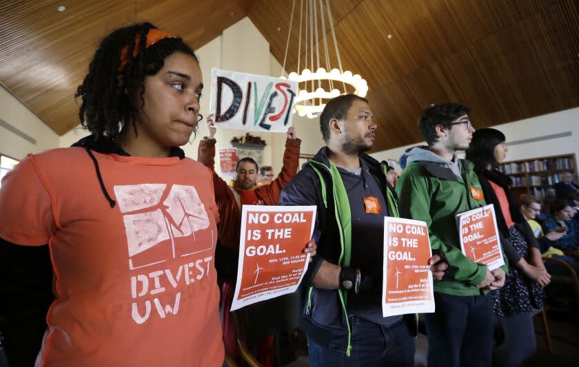 University of Washington senior Sarra Tekola, left, stands with other protesters at a Board of Regents meeting Thursday, Nov. 13, 2014, in Seattle. Members of the student group Confronting Climate Change spoke at the meeting, asking the school to divest itself from direct holdings in oil sands and coal. (AP Photo/Elaine Thompson)