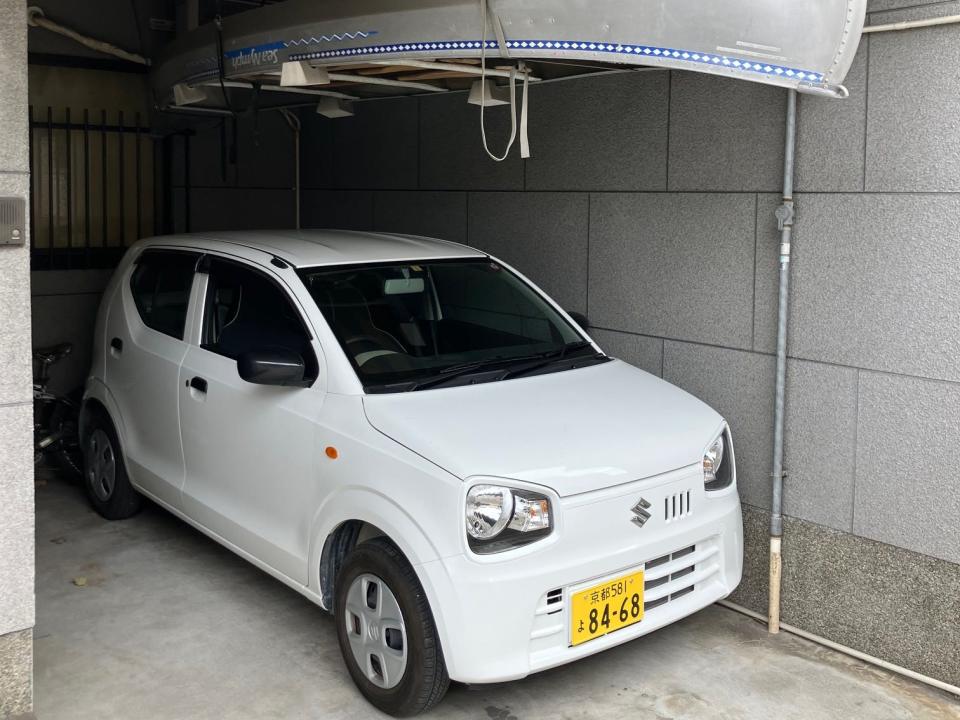 A Suzuki Alto parked underneath a canoe