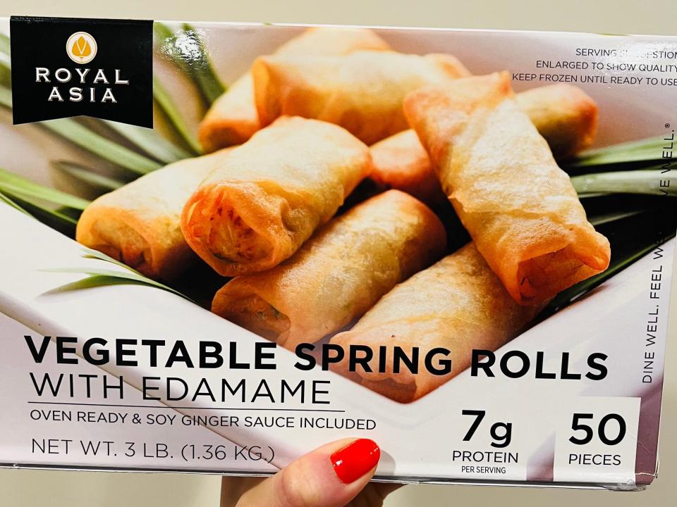 A box with a black "Royal Asia" logo in left hand corner and a picture of eight spring rolls on bed of leaves with "Vegetable Spring Rolls with Edamame" in front