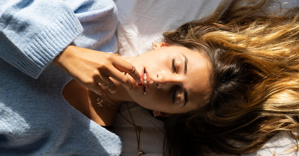 Portrait of beautiful young woman lying in bed with closed eyes