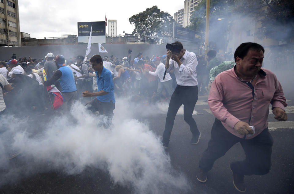 People run from tear gas fired by police dispersing an opposition march in Caracas, Venezuela, Tuesday, March 10, 2020. U.S.-backed Venezuelan political leader Juan Guaido led the march aimed at retaking the National Assembly legislative building, which opposition lawmakers have been blocked from entering. (AP Photo/Matias Delacroix)