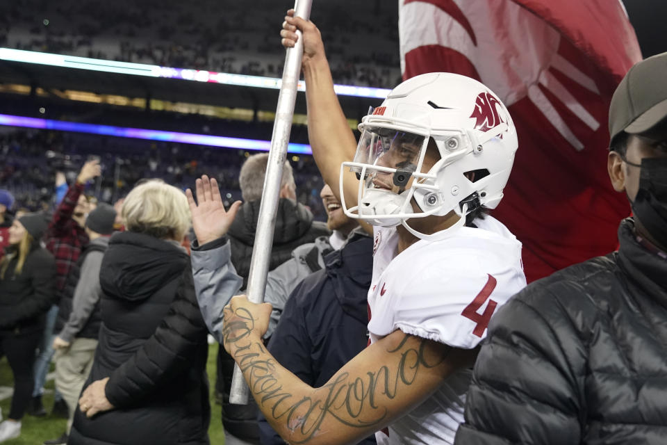 Washington State quarterback Jayden de Laura carries a Cougar flag on the field after WSU defeated Washington 40-13 in an NCAA college football game Friday, Nov. 26, 2021, in Seattle. (AP Photo/Ted S. Warren)