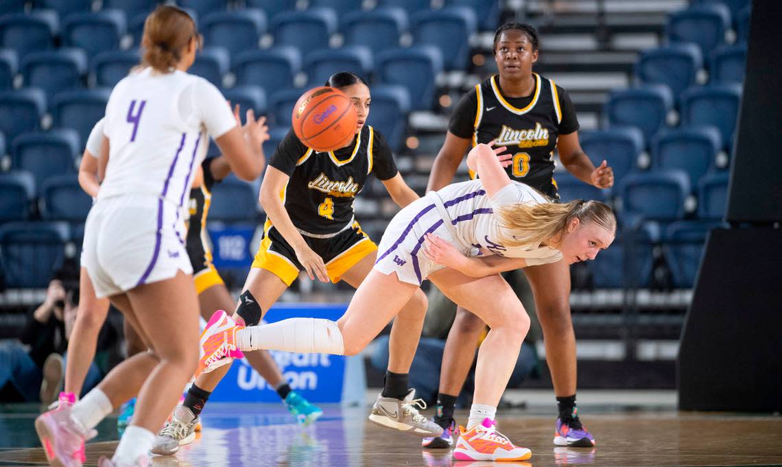 Lake Washington’s Sydney Hani dishes off a pass to teammate Angie Helf under pressure from Lincoln defenders Gianna White (4) and DeAndrea Woods Singleton during their state quarterfinal game at the WIAA state basketball tournament in the Tacoma Dome in Tacoma, Washington, on Wednesday, March 1, 2023. Lake Washington won the game, 57-52.