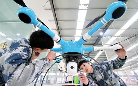 Chinese technicians work on a drone - Credit:  Xinhua