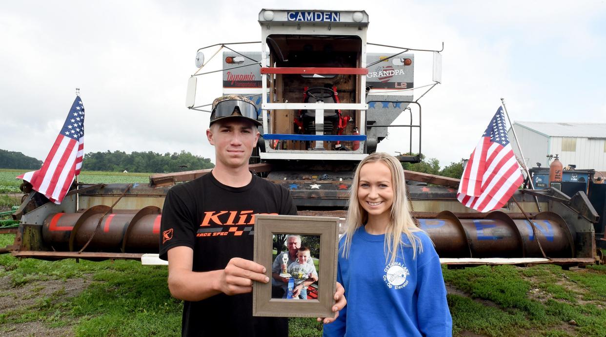 Camden Schmidt, 17, of Monroe holds a photograph of himself at age 4 and his grandpa, Robert Kuehnlein. Camden is shown with his sister, Jaren, 19, who helped create the combine design that honors their grandfather.