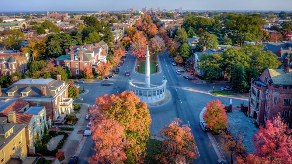 An aerial view above beautiful Fall foliage on Monument Avenue and the skyline of Richmond Virginia in the distance