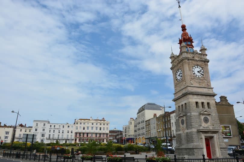 Margate, UK - June 19, 2015: The main clock tower in Margate, Kent. A popular tourist seaside town. Various people in the background walking and driving the streets, shops with logos in the distance.