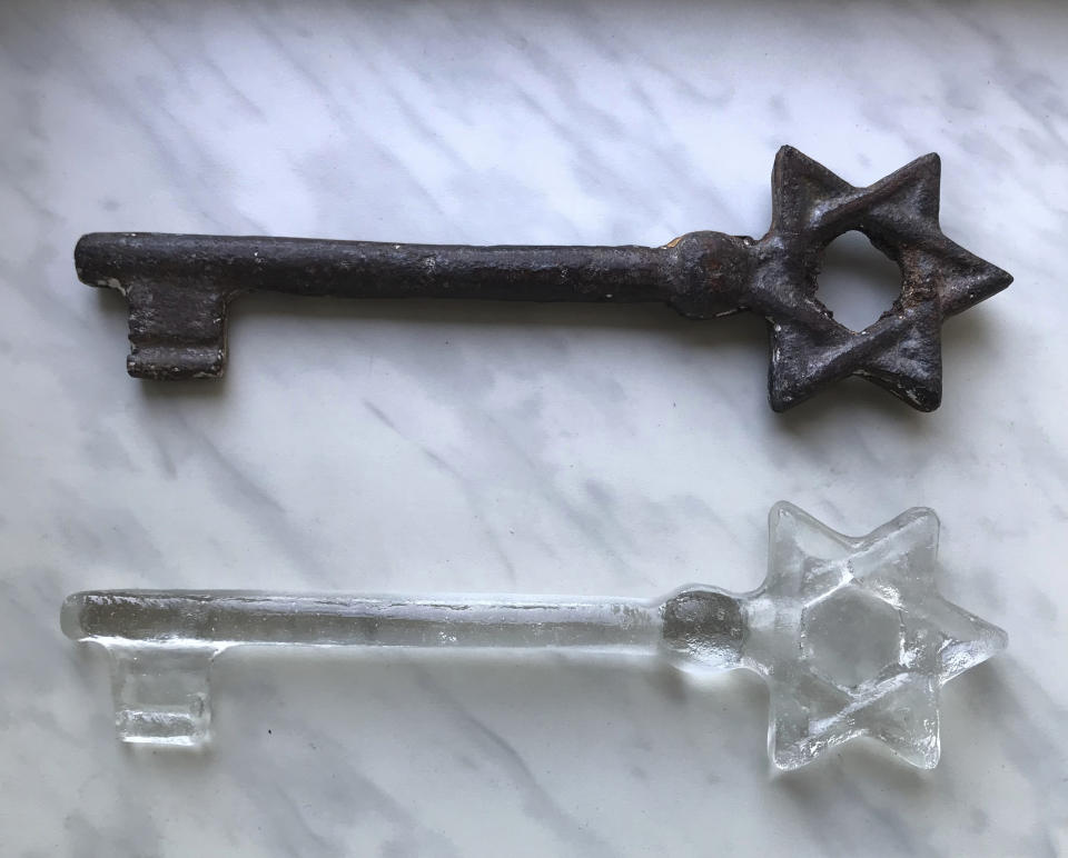 In this undated photo provided by artist Rachel Stevens an old synagogue key discovered by Stevens at a market in Lviv, Ukraine, and a glass replica that she made modeled on it are photographed. Seventy-five of the glass replicas were presented to people working to preserve the memory of the Jews of Lviv and the region during a ceremony marking the 75th anniversary of the destruction of the city’s Jewish community in the Holocaust on Sunday Sept. 2, 2018. (Rachel Stevens via AP)