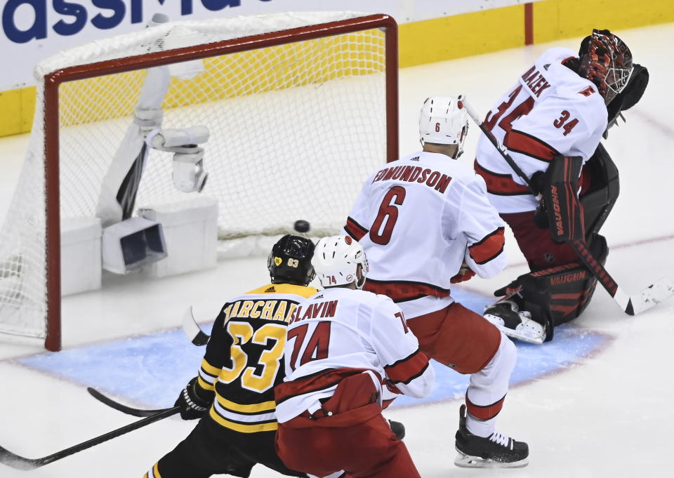 Boston Bruins left wing Brad Marchand (63) watches the game-winning goal go past Carolina Hurricanes goaltender Petr Mrazek (34) as Hurricanes defenseman Joel Edmundson (6) and Hurricanes defenseman Jaccob Slavin (74) look on during the second overtime period in an NHL hockey Eastern Conference Stanley Cup playoff game in Toronto, Wednesday, Aug. 12, 2020. (Nathan Denette/The Canadian Press via AP)