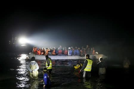 A rescue boat (L) shines a light on a dinghy carrying refugees and migrants as it approaches the shore near the city of Mytilene on the Greek island of Lesbos, March 20, 2016. REUTERS/Alkis Konstantinidis