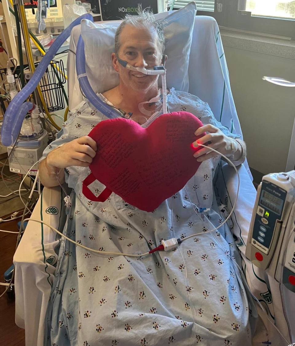 Jason Brown holds up a heart, signifying his heart transplant, while in the hospital in Charlotte.