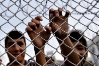 A migrant grabs a razor wire topped fence as the Greek prime minister visits a refugee and migrant registration camp in Mytilene, on the Greek island of Lesbos, on October 6, 2015