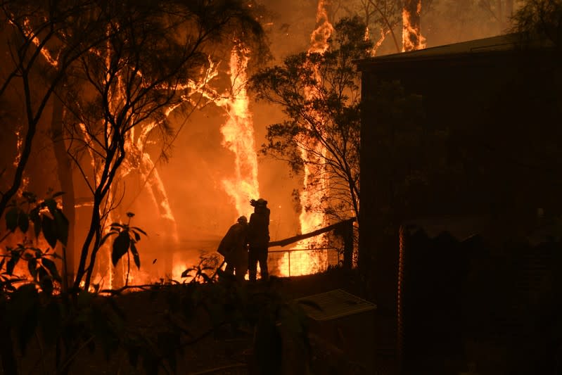 RFS volunteers and NSW Fire and Rescue officers protect a home on Wheelbarrow Ridge Road being impacted by the Gospers Mountain fire near Colo Heights south west of Sydney