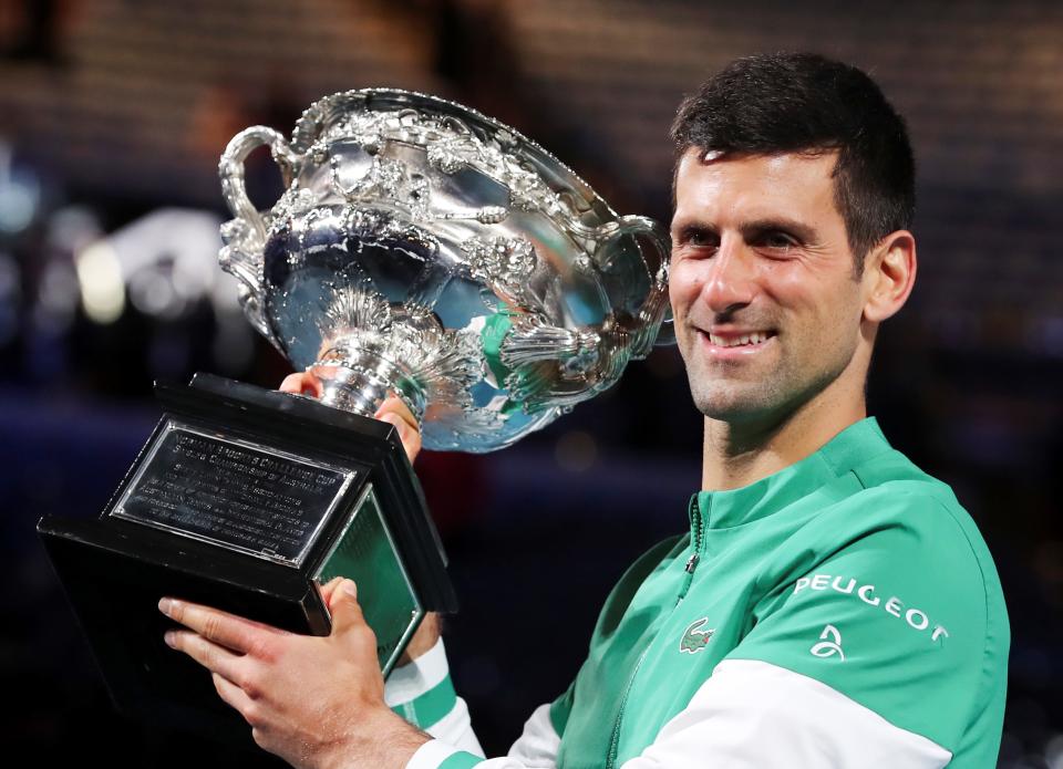 Novak Djokovic (pictured) smiles and holds the Australian Open trophy.