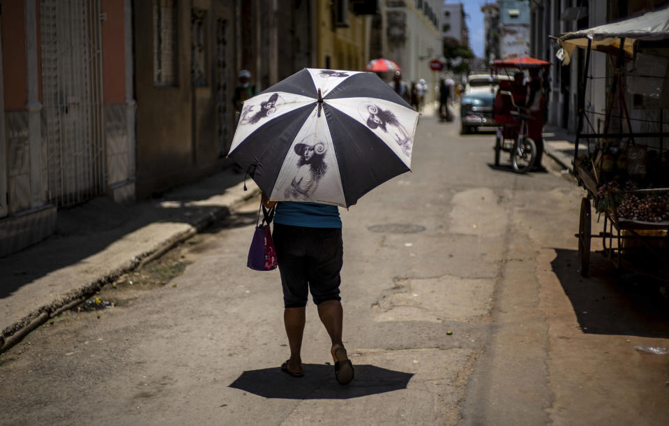 A pedestrian shades herself with an umbrella in Havana, Cuba, Wednesday, July 5, 2023. The entire planet sweltered for the two unofficial hottest days in human record keeping Monday and Tuesday, according to University of Maine scientists at the Climate Reanalyzer project. (AP Photo/Ramon Espinosa)