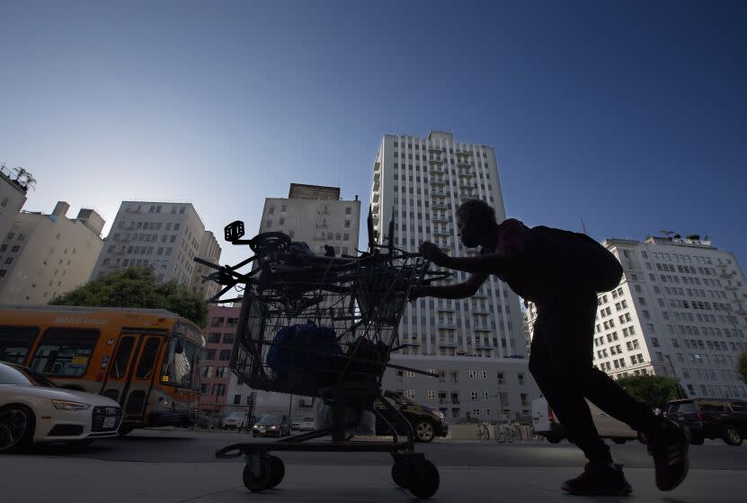 LOS ANGELES, CA - AUG. 6, 2020. A man pushes a shopping cart along the sidewalk in the historc urban core of Los Angeles on Thursday, Aug. 6, 2020. Motor and foot traffic downtown has thinned considerably since the pre-coronavirus days of five months ago. (Luis Sinco/Los Angeles Times)