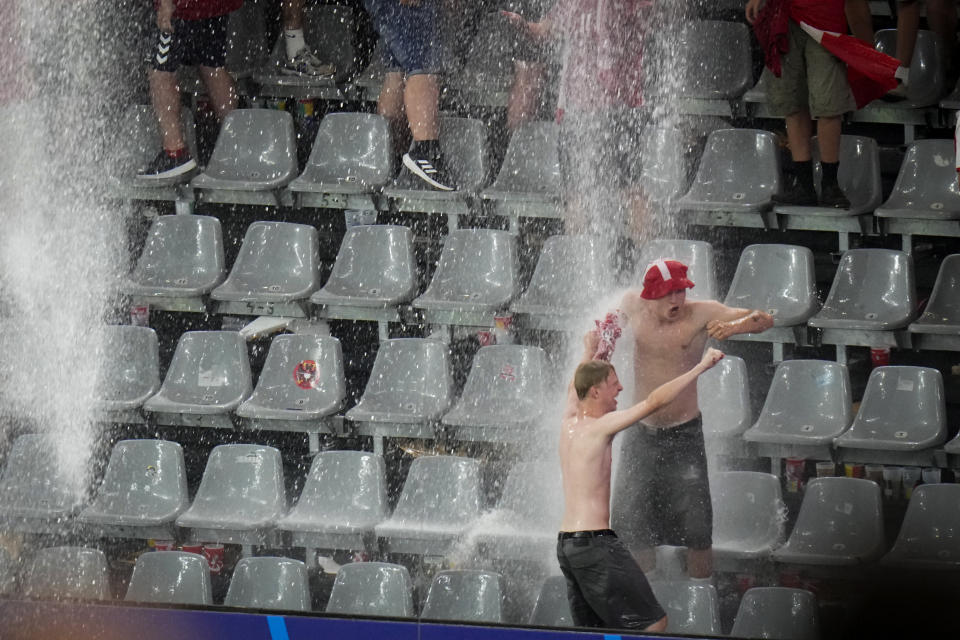 Fans dance in the rain as the round of sixteen match between Germany and Denmark at the Euro 2024 soccer tournament was suspended due to adverse weather in Dortmund, Germany, Saturday, June 29, 2024. (AP Photo/Hassan Ammar)