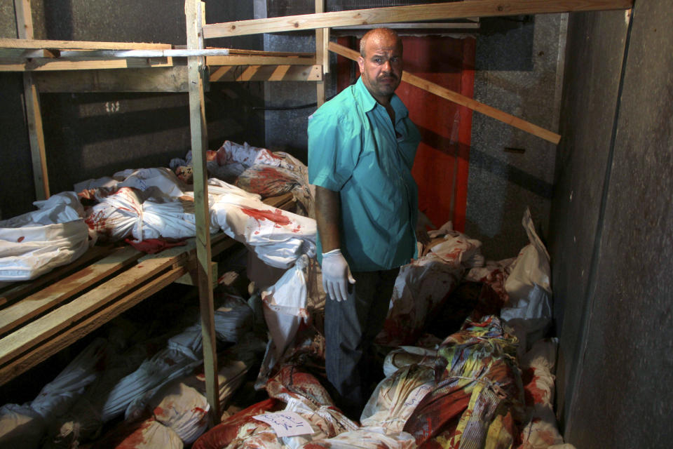 FILE - In this Aug. 2, 2014 file photo, a medic stands among lifeless bodies of people killed in the Gaza war that are stored in a food refrigerator as the town's morgue has run out of space in Rafah, southern Gaza Strip. The Israeli military said on Wednesday Aug. 15, 2018, its investigation focused on an Aug. 1, 2014, battle in the southern Gaza town of Rafah, one of the bloodiest incidents of the 2014 war in the Gaza Strip, has found no criminal wrongdoing by Israeli forces, although human rights advocates accused the military of a whitewash.(AP Photo/Hatem Ali, File)