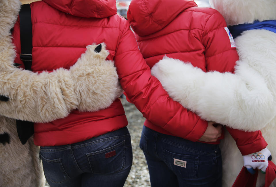 Two spectators pose for photos with Sochi Olympics mascots during the snowboard parallel giant slalom qualifying round at the Rosa Khutor Extreme Park, at the 2014 Winter Olympics, Wednesday, Feb. 19, 2014, in Krasnaya Polyana, Russia.