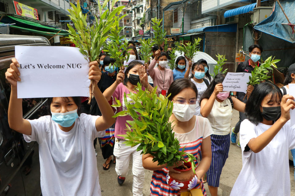 Anti-coup protesters hold leaf branches and signs to welcome the NUG, or national unity government as they march Saturday, April 17, 2021 in Yangon, Myanmar. Opponents of Myanmar’s ruling junta have declared they have formed an interim national unity government with members of Aung San Suu Kyi’s ousted cabinet and major ethnic minority groups. (AP Photo)