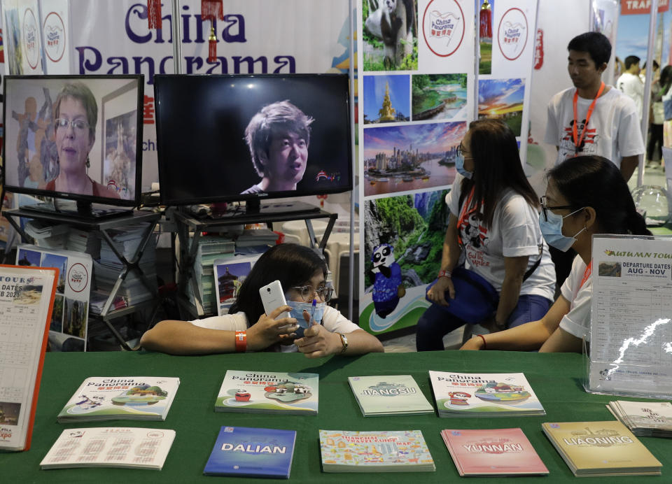 People wearing protective masks sit inside their booth promoting China during a travel fair in Manila, Philippines on Friday, Feb. 7, 2020. The organizer said the impact of travel bans due to the new virus has already affected tourism in the Philippines due to the huge Chinese market. Asian nations have profited handsomely from the impressive growth in tourists from China over the past decade, but the specter of a rapidly spreading virus has raised concerns over the industry prospects. (AP Photo/Aaron Favila)