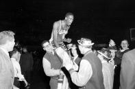 FILE - University of San Francisco basketball player Bill Russell is carried from the floor of Kansas City's Municipal Auditorium by students celebrating a win over La Salle for the NCAA basketball championship, March 19, 1955. (AP Photo/Bill Streator, File)