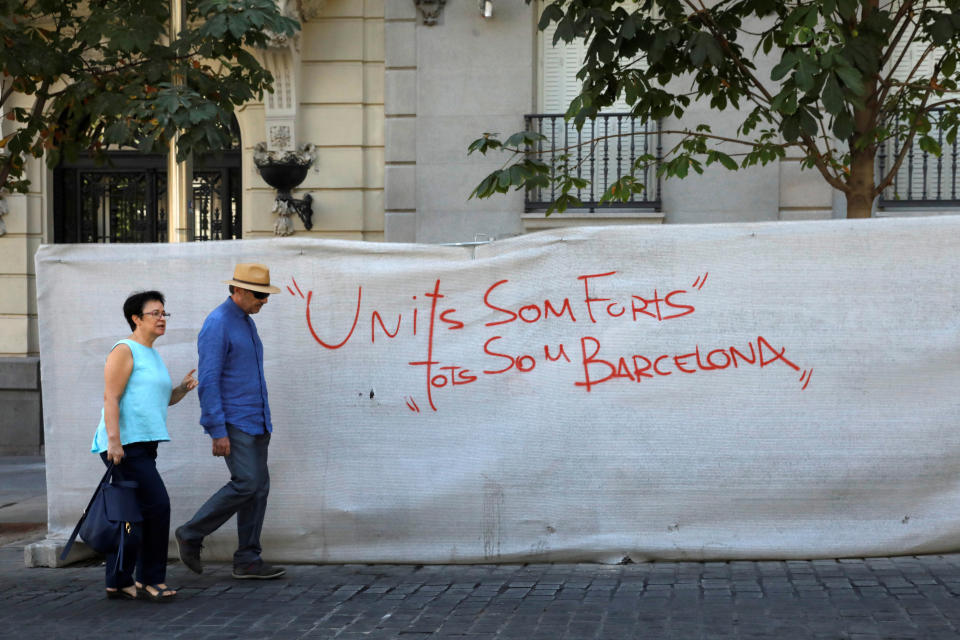 A couple walks past a graffiti message that reads, "United we are strong, we are all Barcelona" in the Spanish capital of Madrid on Friday.
