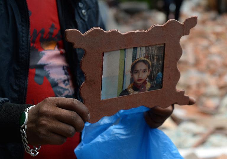 A Nepalese resident holds a photograph of earthquake victim Prasamsah, 14, as her body is recovered during rescue efforts in the Balaju neighbourhood of Kathmandu, on April 27, 2015
