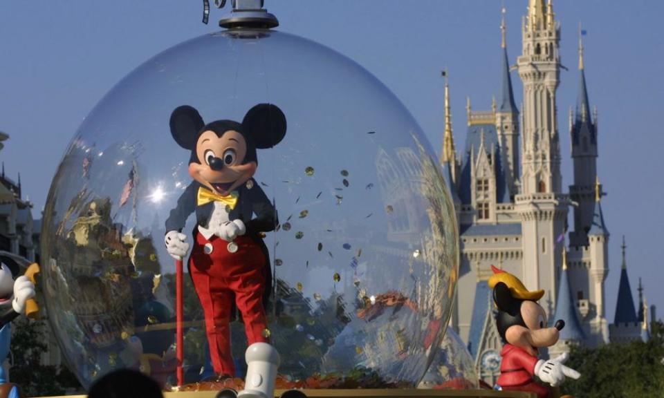 Mickey Mouse rides in a parade through Main Street, USA, with Cinderella’s castle in the background at Disney World’s Magic Kingdom